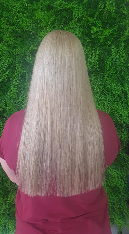 Long straight blonde hair against a green wall